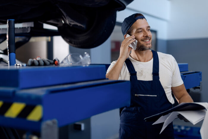 Un mécanicien dans son garage, parle au téléphone avec les experts de Hotline Logicat.